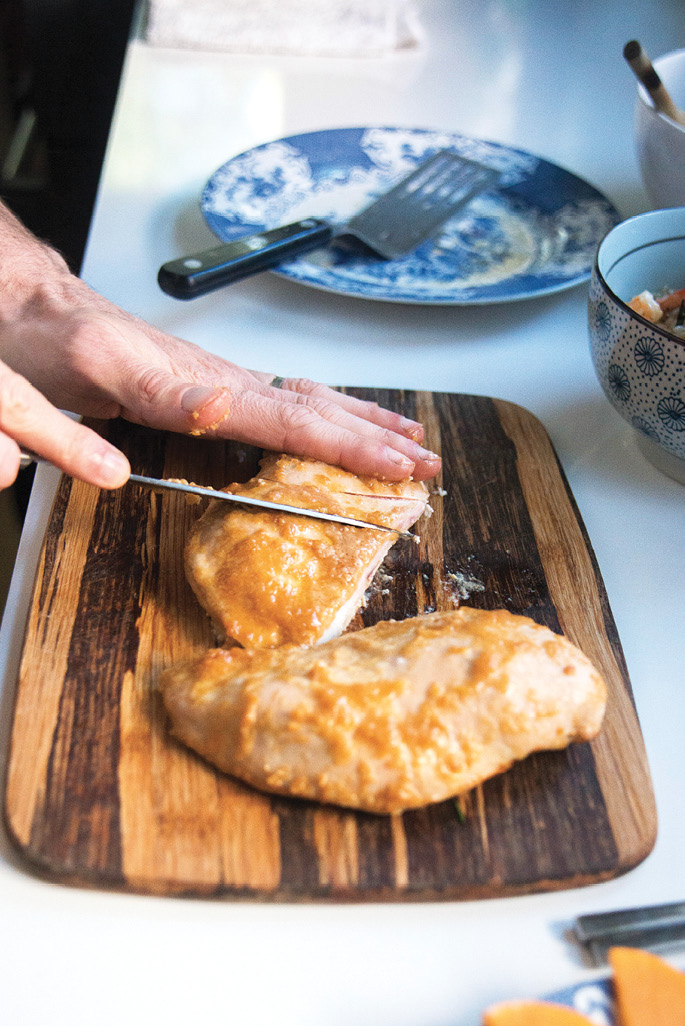 To serve the miso chicken, slice the cooked breasts on the diagonal. Walker plates his with an arrangement of seasonal fruit.