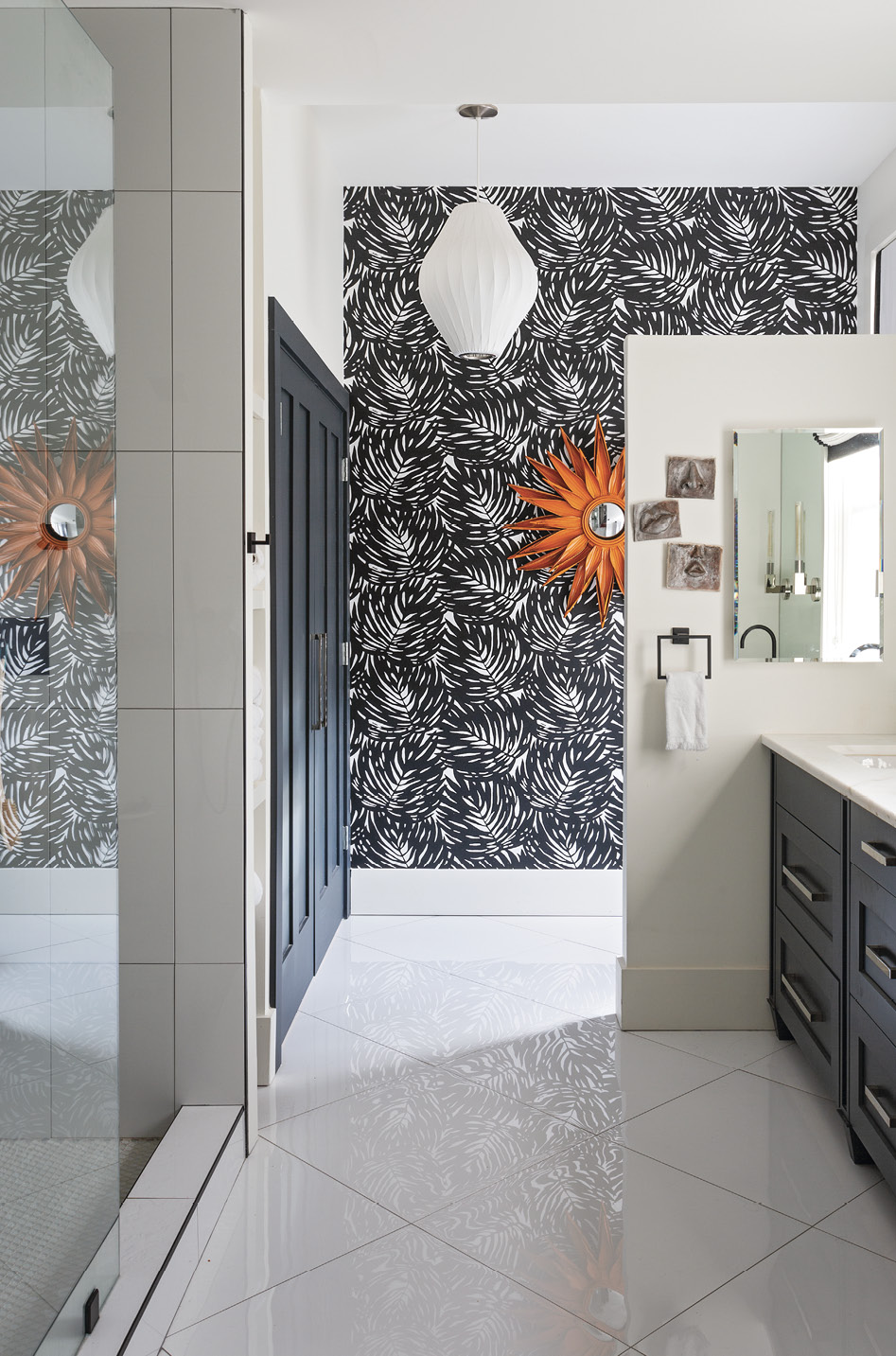 Space Saver: The master bath required significant reconfiguring—gone are the bathtub, window, and door to the piazza—to accommodate a closet, laundry room, and walk-in shower. An orange mirror provides a pop of color on the graphic palm frond wallpaper from Serena &amp; Lily.