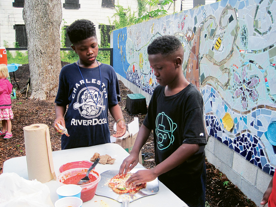 Young pizza-partiers make pies to slide into the cob oven that was built by architect April McGill and mosaicked by artist Meryl Weber.