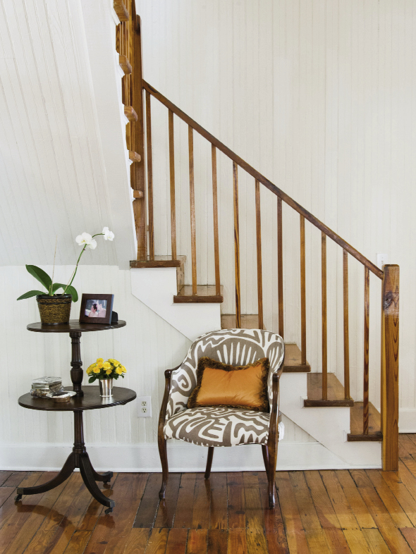 A mahogany pedestal table paired with a patterned armchair.