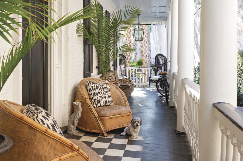 The furnishings on the piazza, such as the bold patterned pillows from Fritz Porter and the circa-1930s rattan chairs, hint at the blend of modern and vintage styles within.