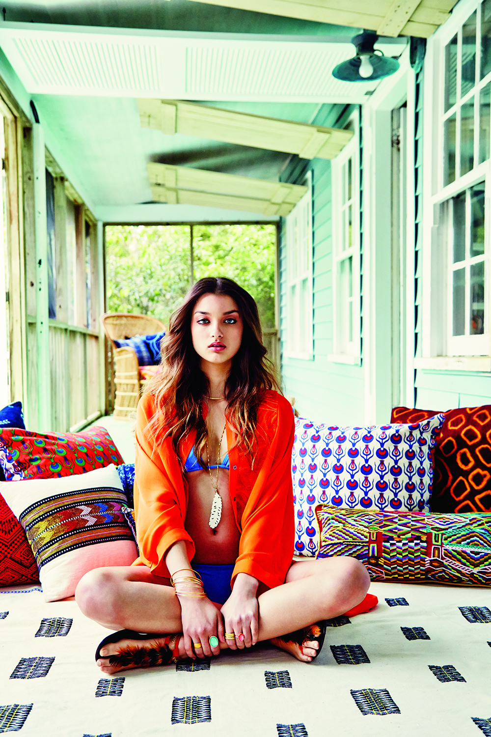 Eres “Les Essentiels Mouna” triangle bikini top and “Les Essentiels Malou” briefs, $286 for both at Bits of Lace; Mantu silk button-up, price upon request at RTW; Roberto Coin “Primavera” 18K gold necklace, $1,500 at Paulo Geiss; Kate Davis carved bone feather and aquamarine on a 22K gold-plated rice chain, $178 at katedavisjewelry.com; “Viseu” crystal bangles, $42 each at Moon and Lola; Van H. Designs 14K gold-plated bangles, $38 each, and 18K matte gold band, $80, all at The Spa at Belmond Charleston Place; Aaron Henry 19K gold bamboo narrow ring guard, $1,190; Aaron Henry 19K gold bamboo wide ring guard, $1,800; and 18K rose gold band with .16 ct. diamonds, $595; all at Croghan’s Jewel Box; Kate Davis 24K gold ”Abaco Anklet” with sea-horse charm, $85 at katedavisjewelry.com; and Pura Lopez “Fatmire” sandal, $298 at Shoes on King Props: peacock printed pillows from ESD, blue pillow with raffia fringe from CHD Interiors, remaining pillows and blanket from IBU, and rattan chair from Charleston Revisions